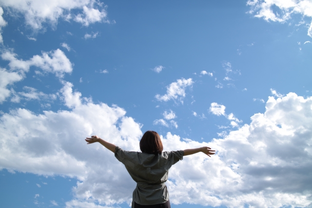 空に向かって手を広げる女性